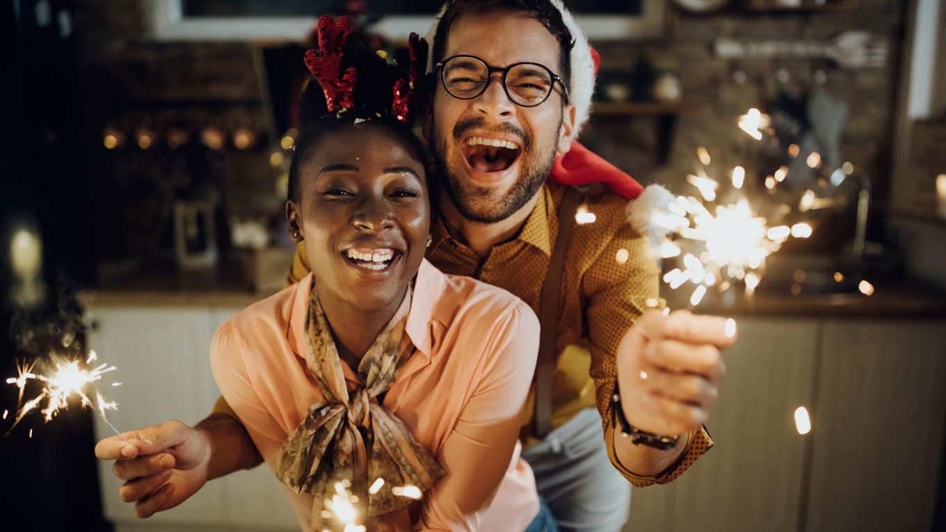 cheerful couple having fun with sparklers on New Year's eve at home.