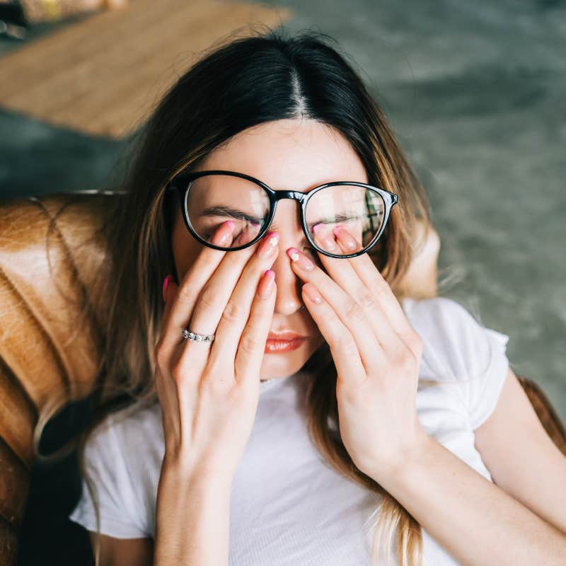 Young woman rubs her eyes after using glasses