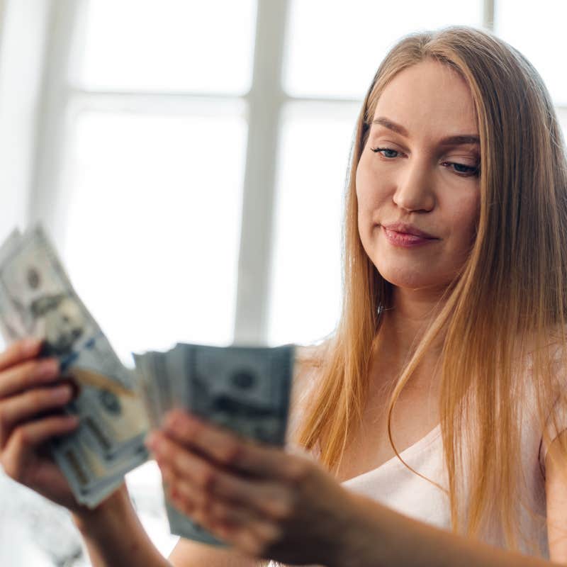 Blonde long-haired woman counting money at home