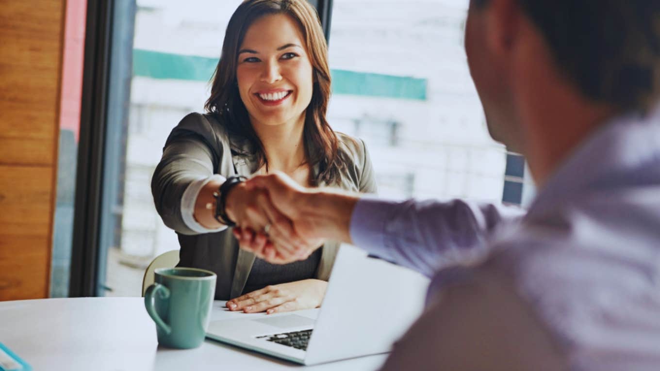 woman in office shaking hands with man 