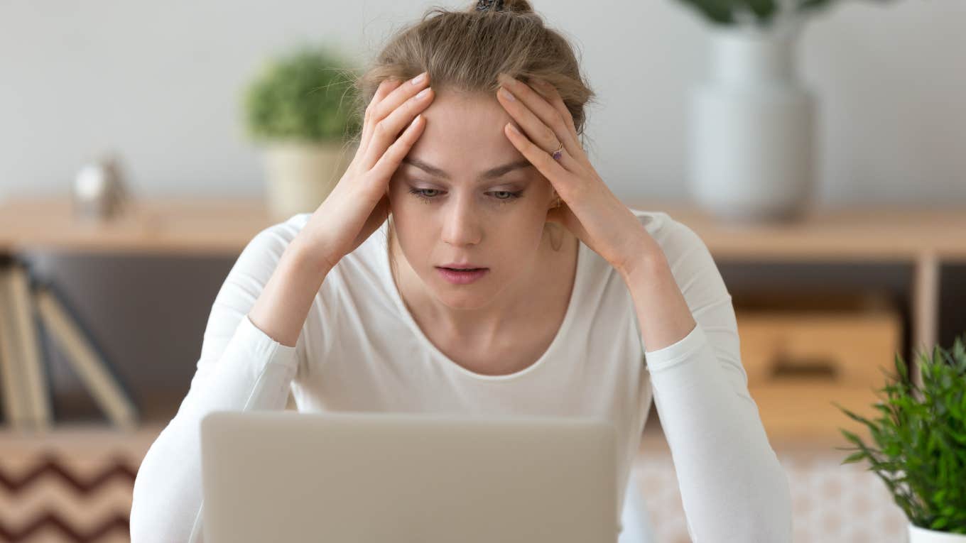 frustrated woman with hands on her forehead looking at laptop