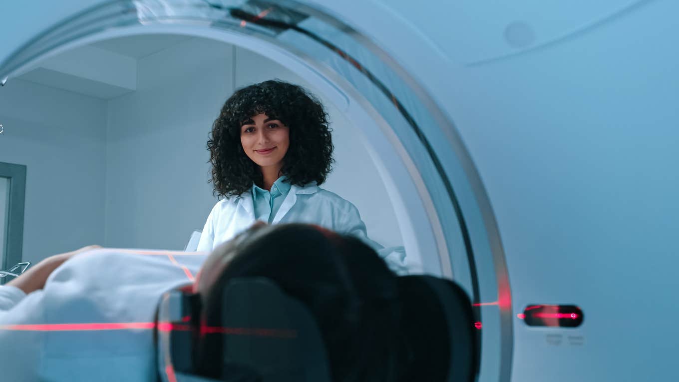 radiologist smiling down at patient being rolled into MRI machine