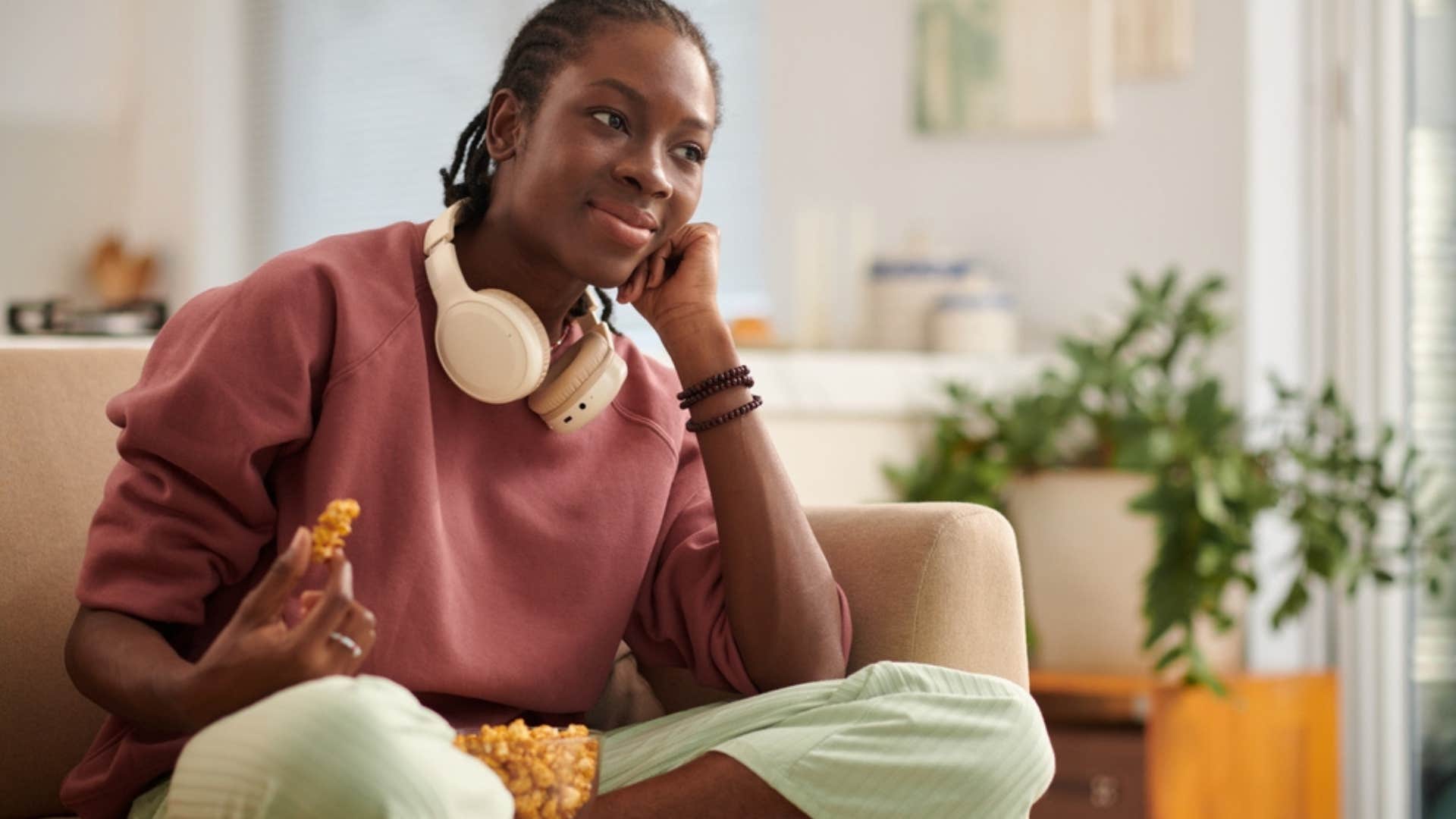 Woman relaxing while eating food on the couch.