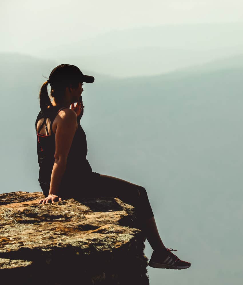 woman sitting at the top of a mountain