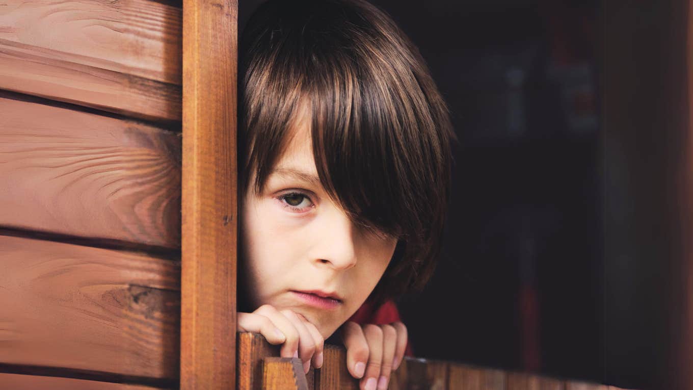 Young boy looking out of treehouse window. 