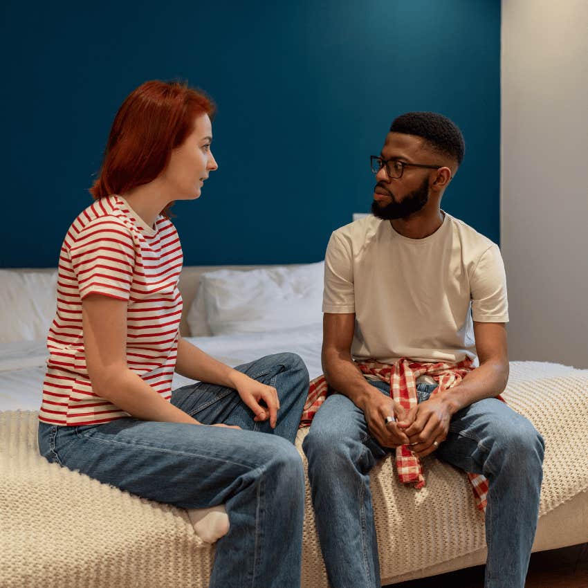 young man and young woman sitting on a bed and talk