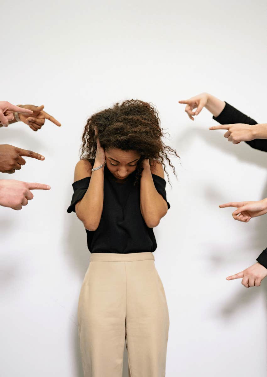 young professional woman surrounded by pointing fingers