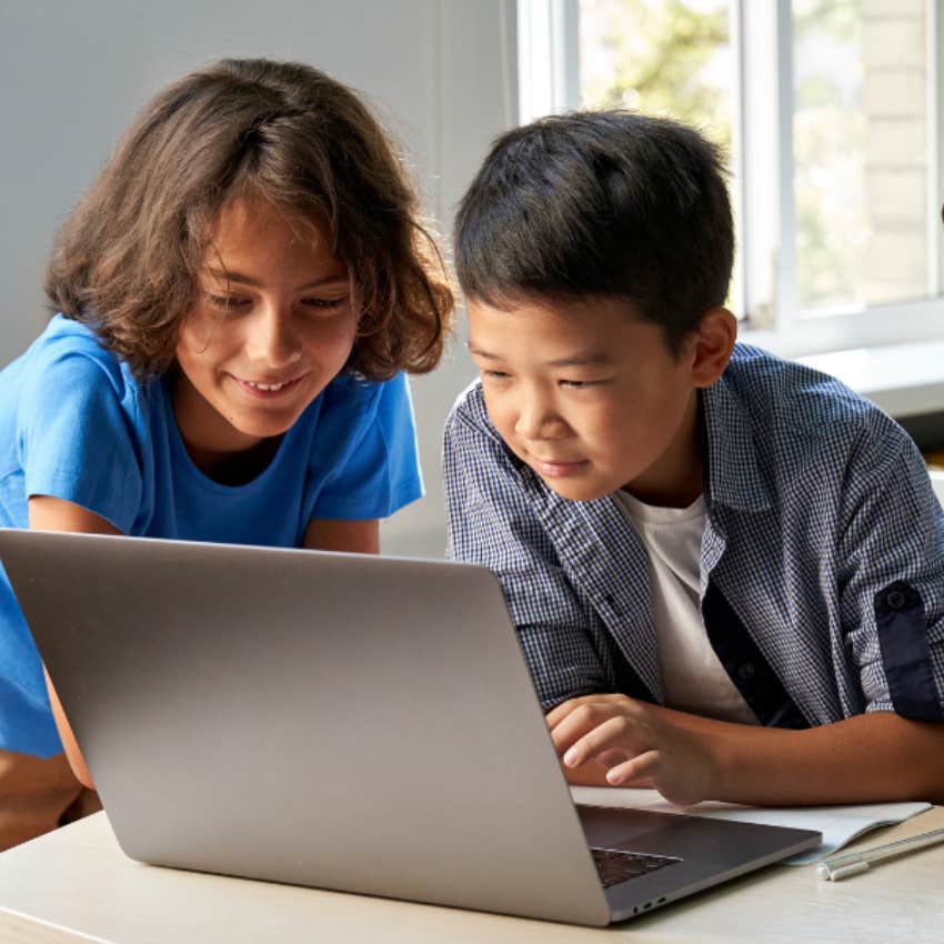 Young students looking at their teacher's laptop. 