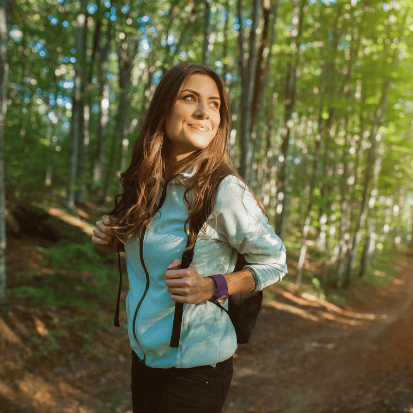 young woman walking a forest trail