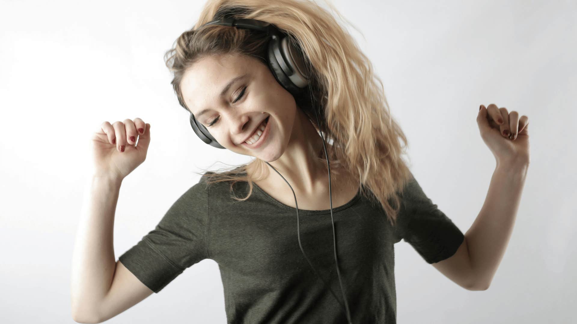 young woman wearing headphones and dancing