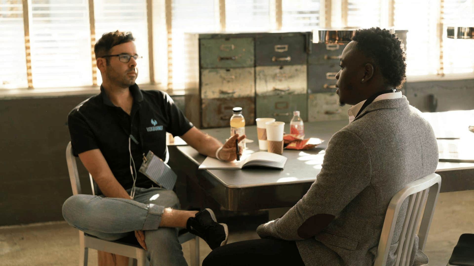 two men talking and sitting at a table