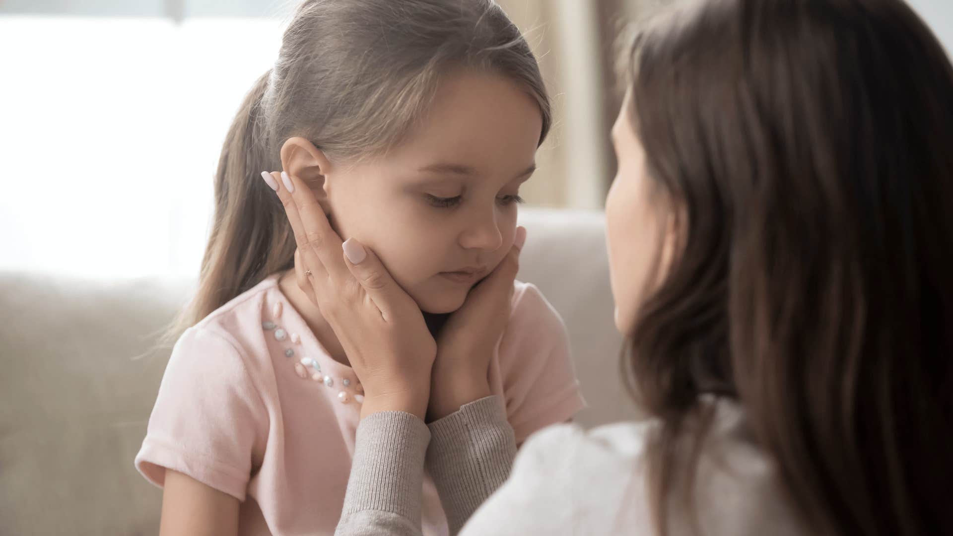 mom cupping young girl's face in her hands