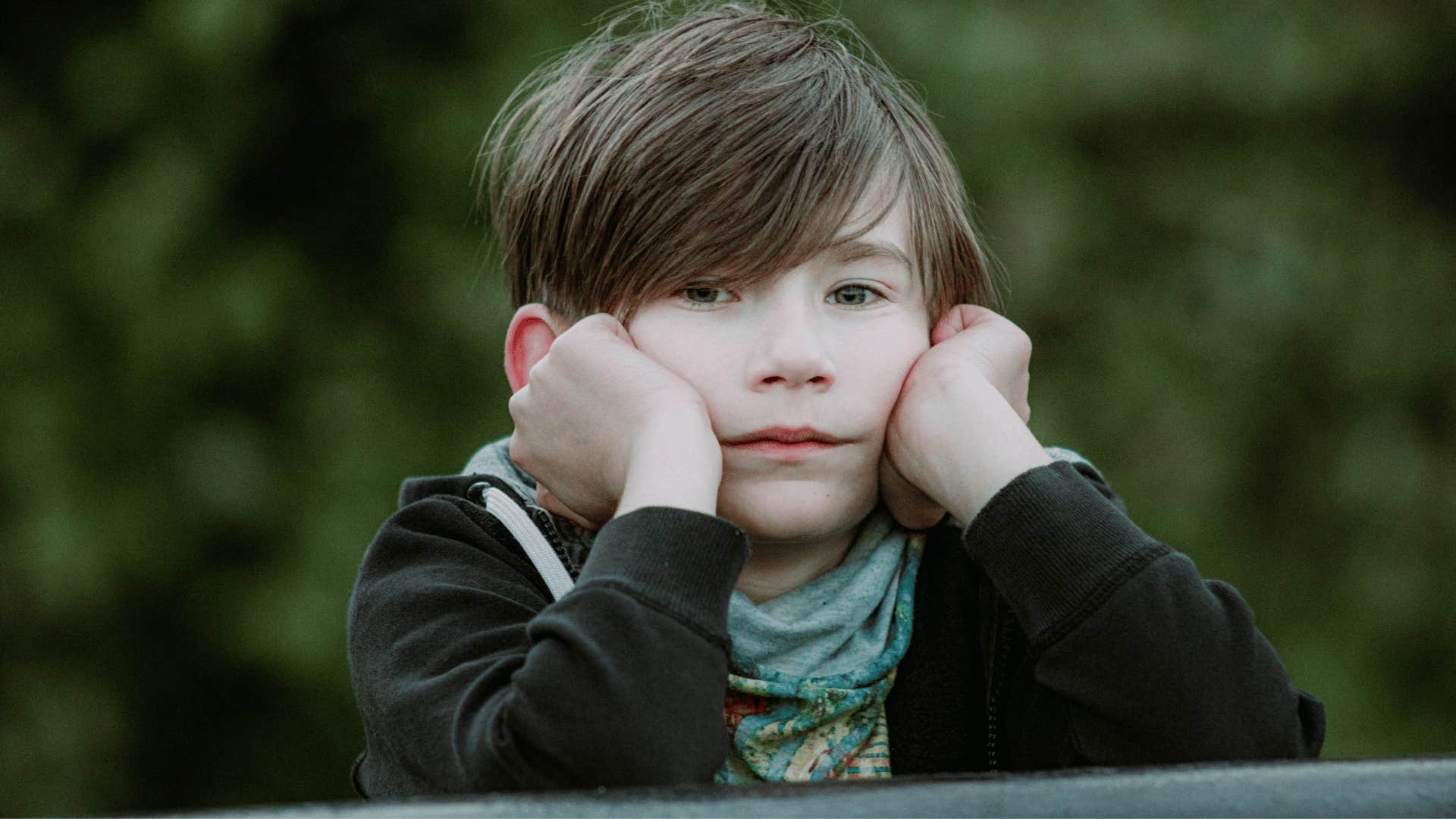 sad young boy with his head in his hands