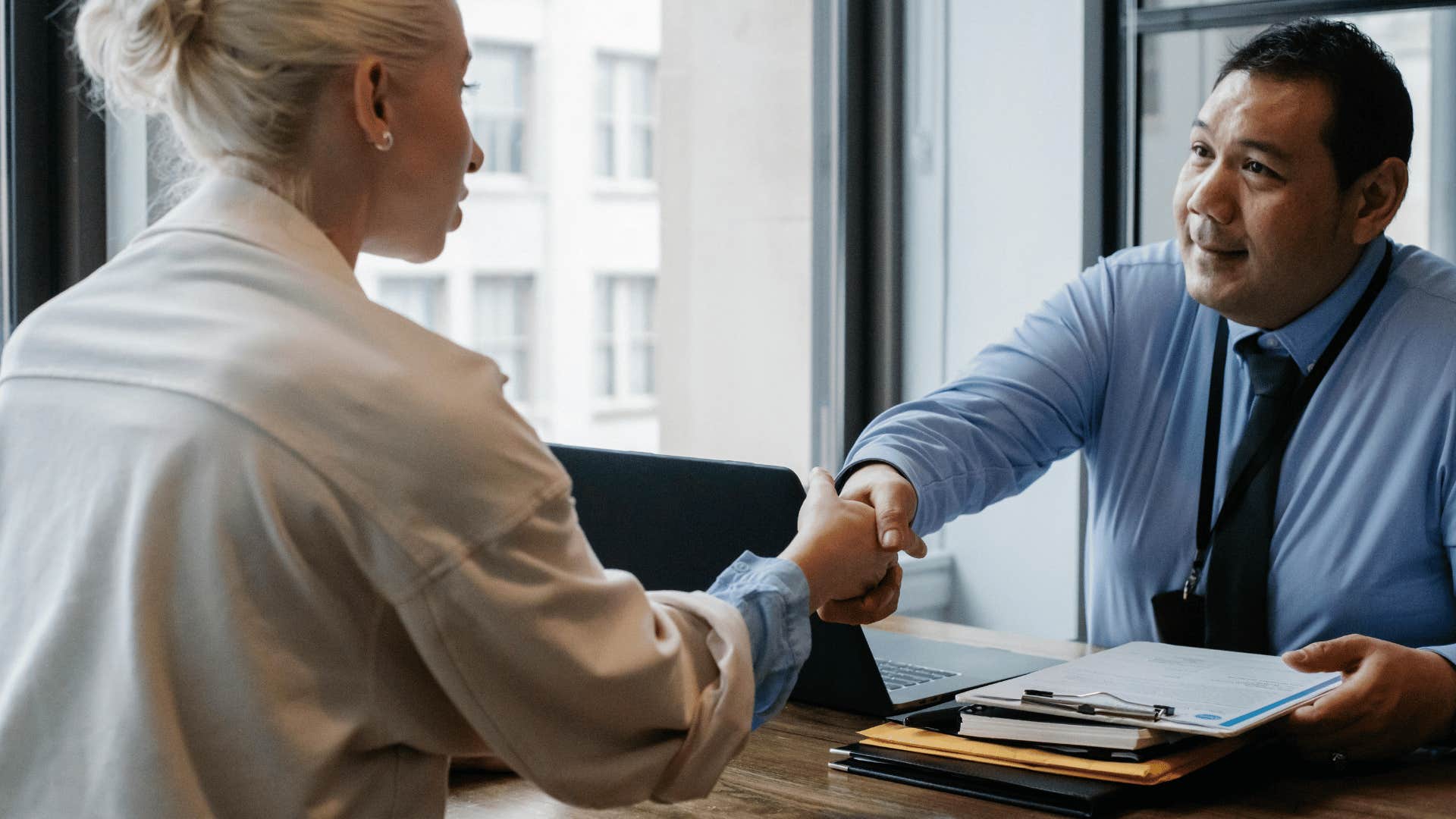 two professionals shaking hands across desk