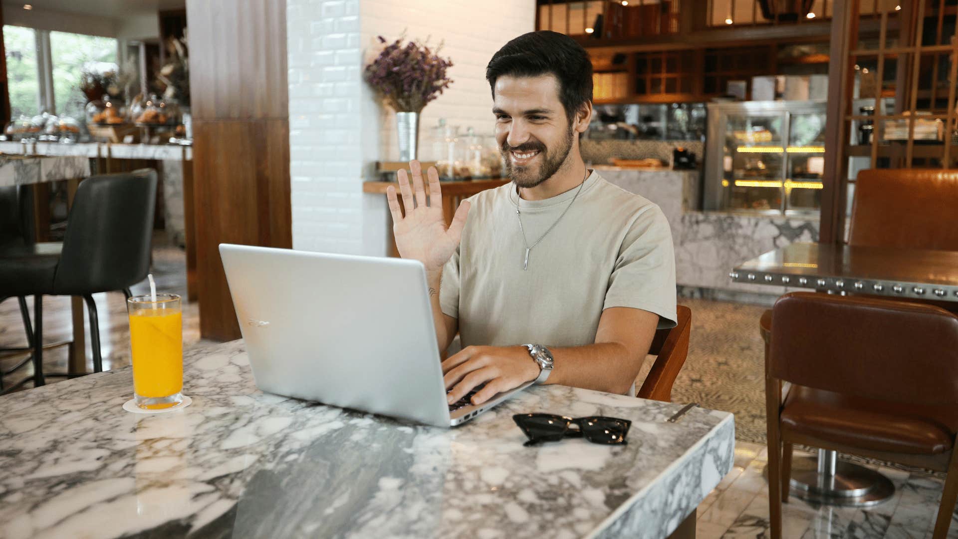 young man waving at someone on laptop