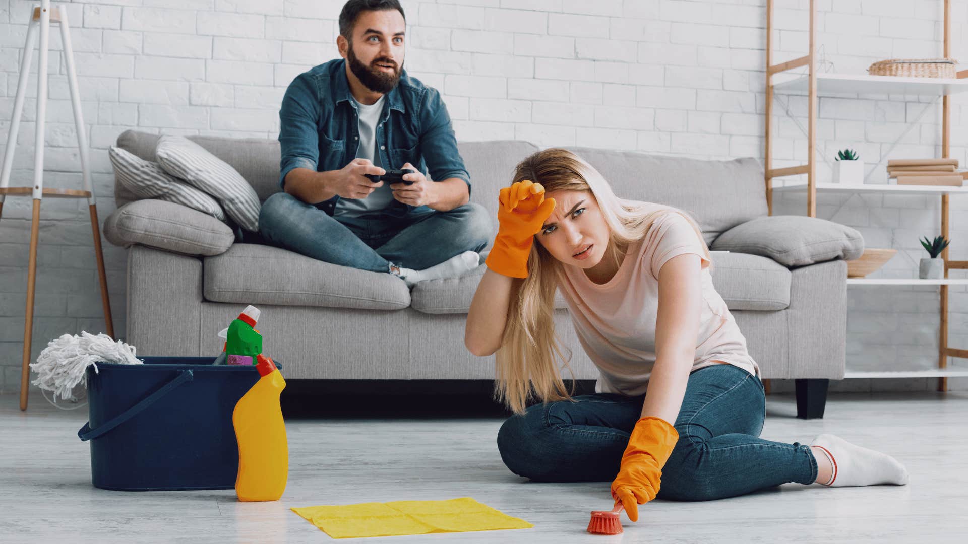 exhausted woman cleaning while man plays games