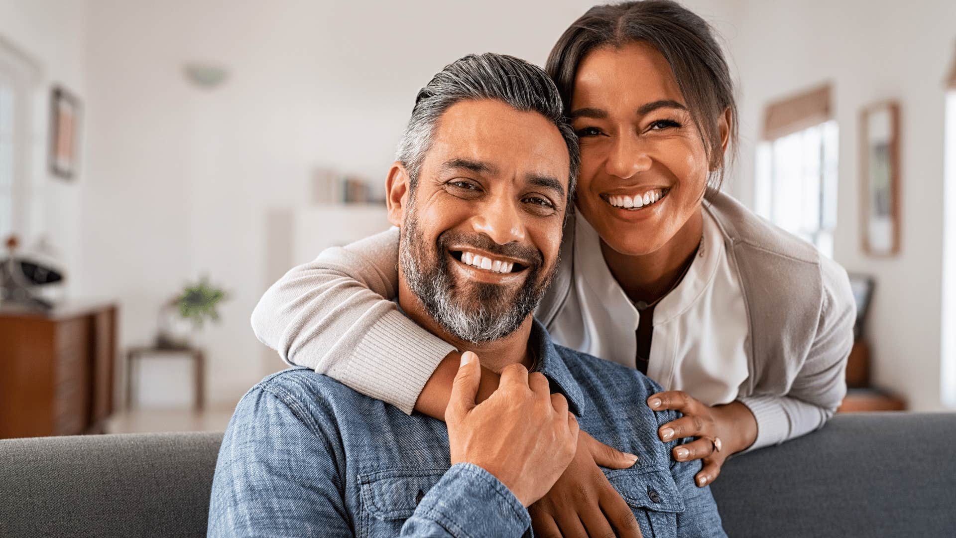 woman leaning over couch and hugging man