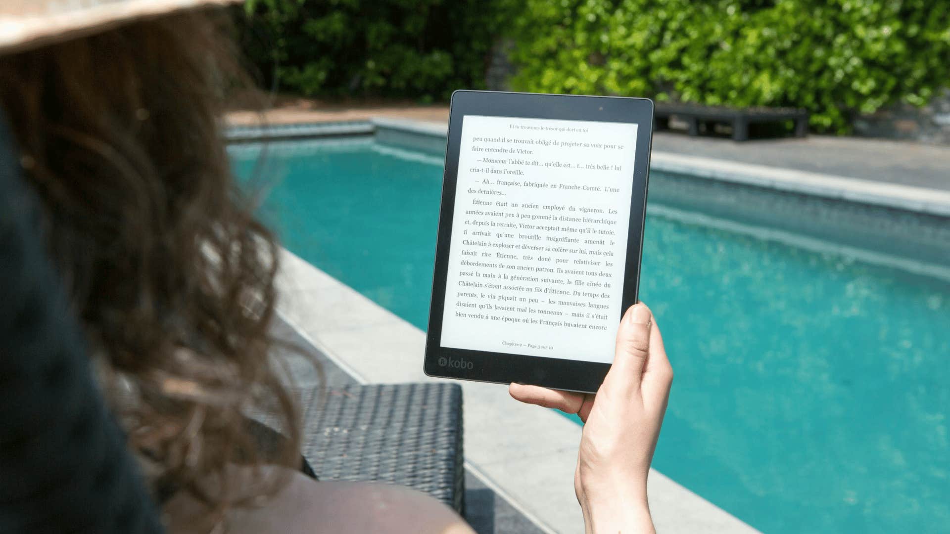 woman at poolside reading on an e-reader