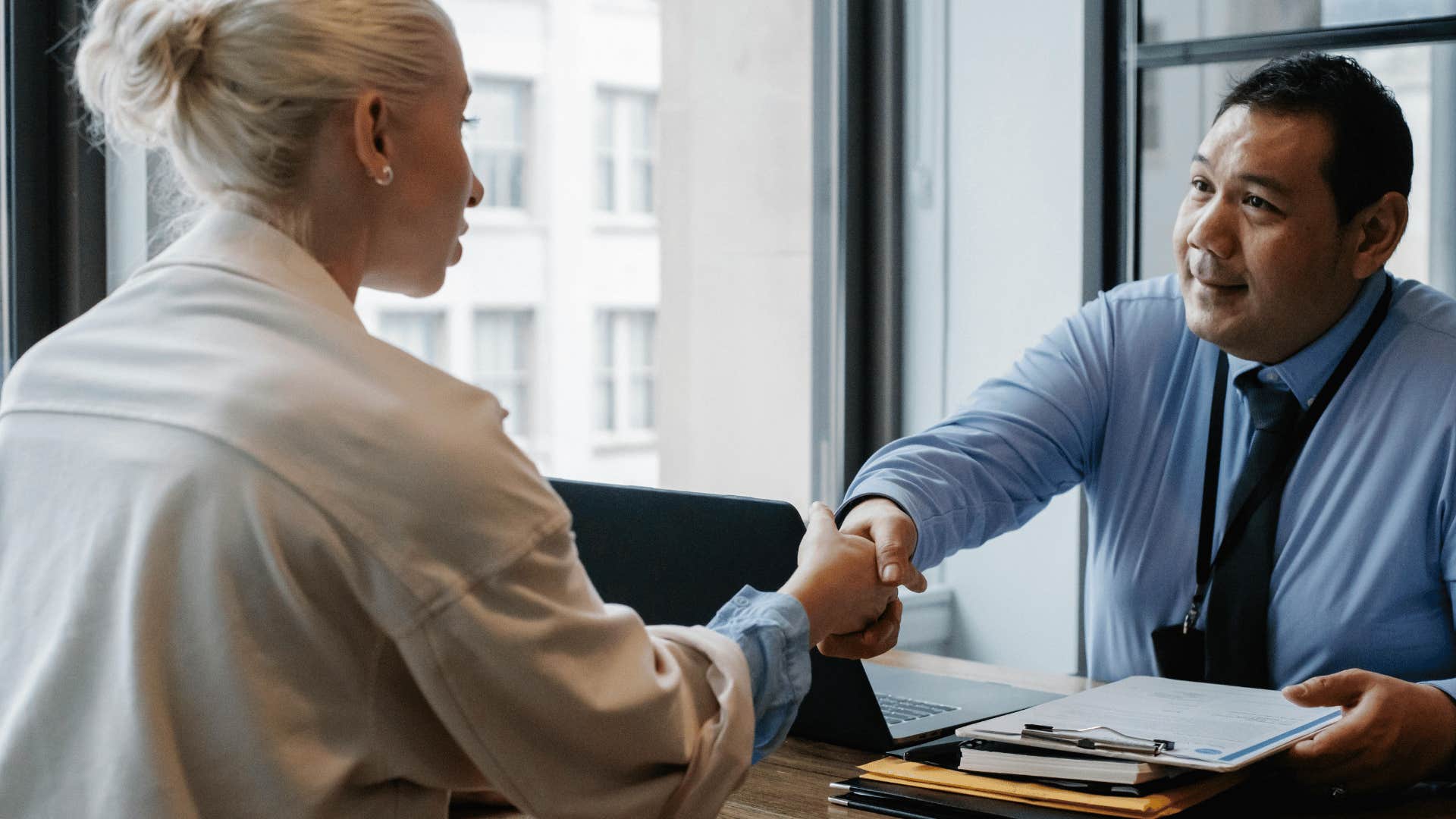 man and woman shaking hands across a desk