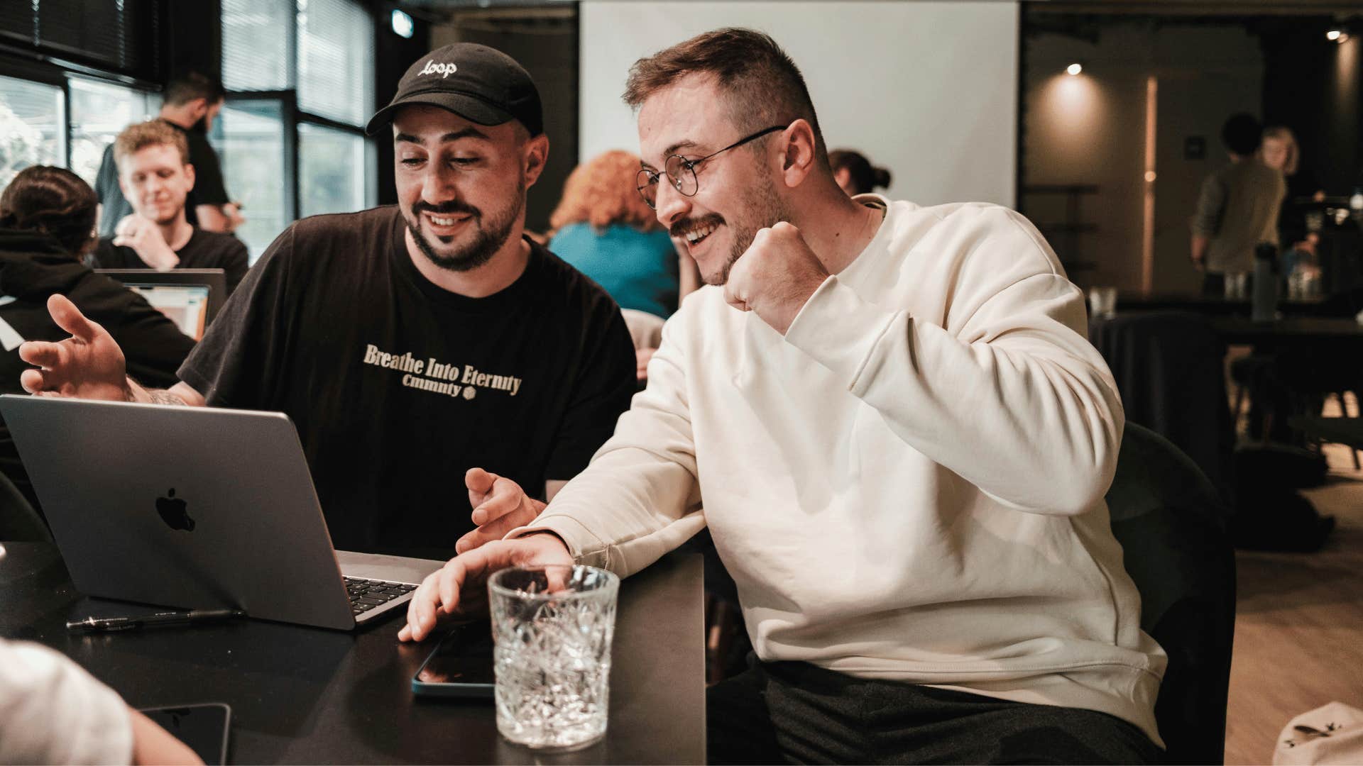 two smiling men working on a laptop together