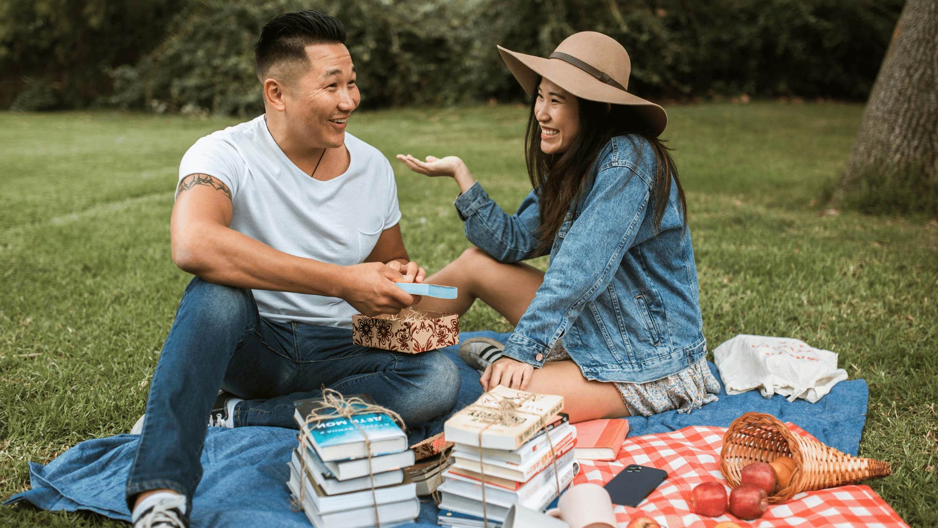 couple sitting outdoors with snacks and bundles of books