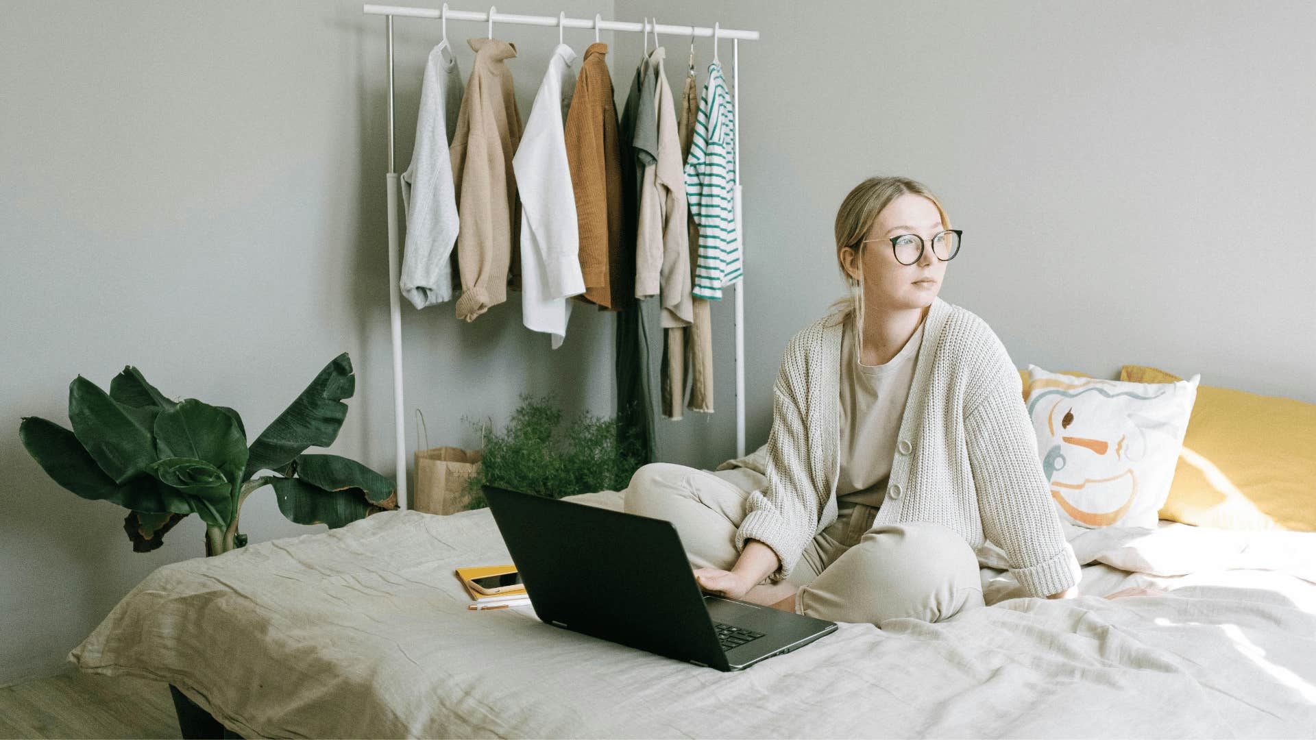 young woman working on a laptop while sitting in bed