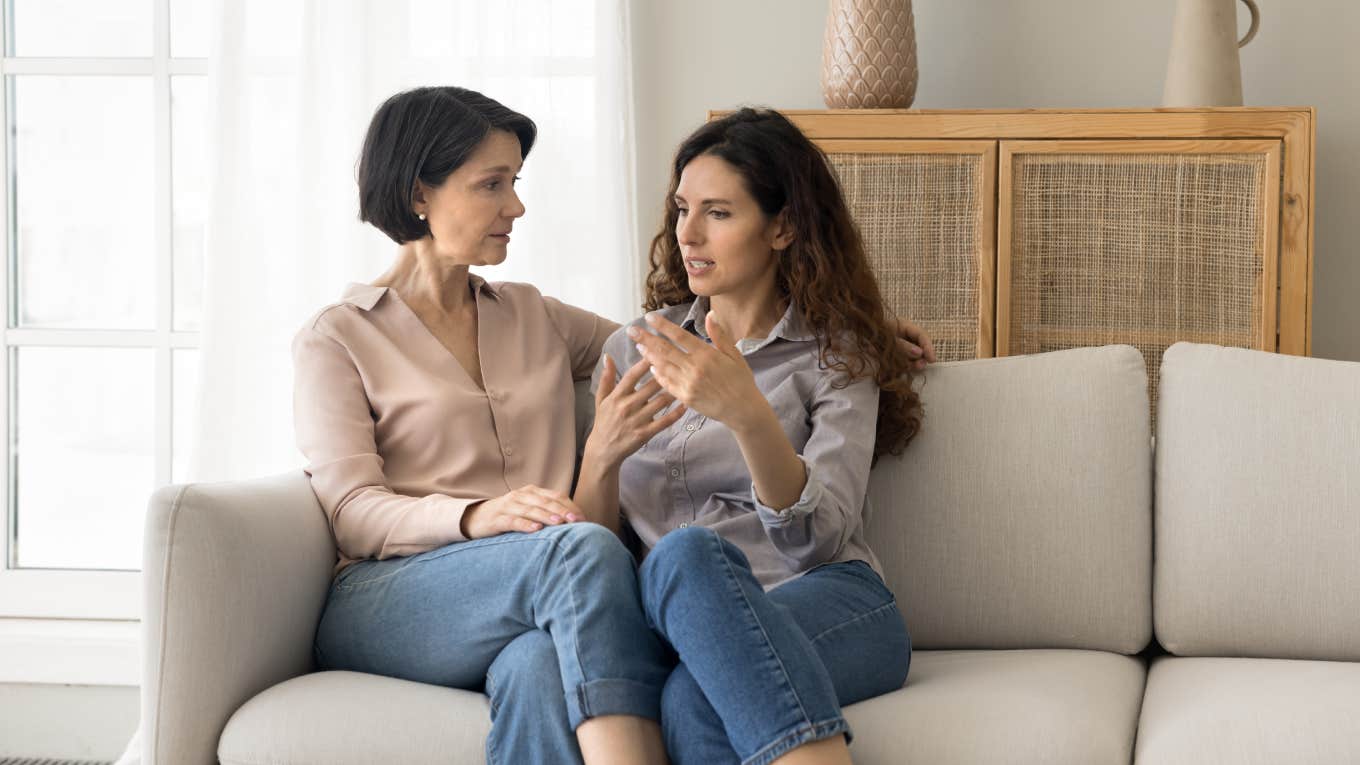 two women having discussion while sitting on couch at home