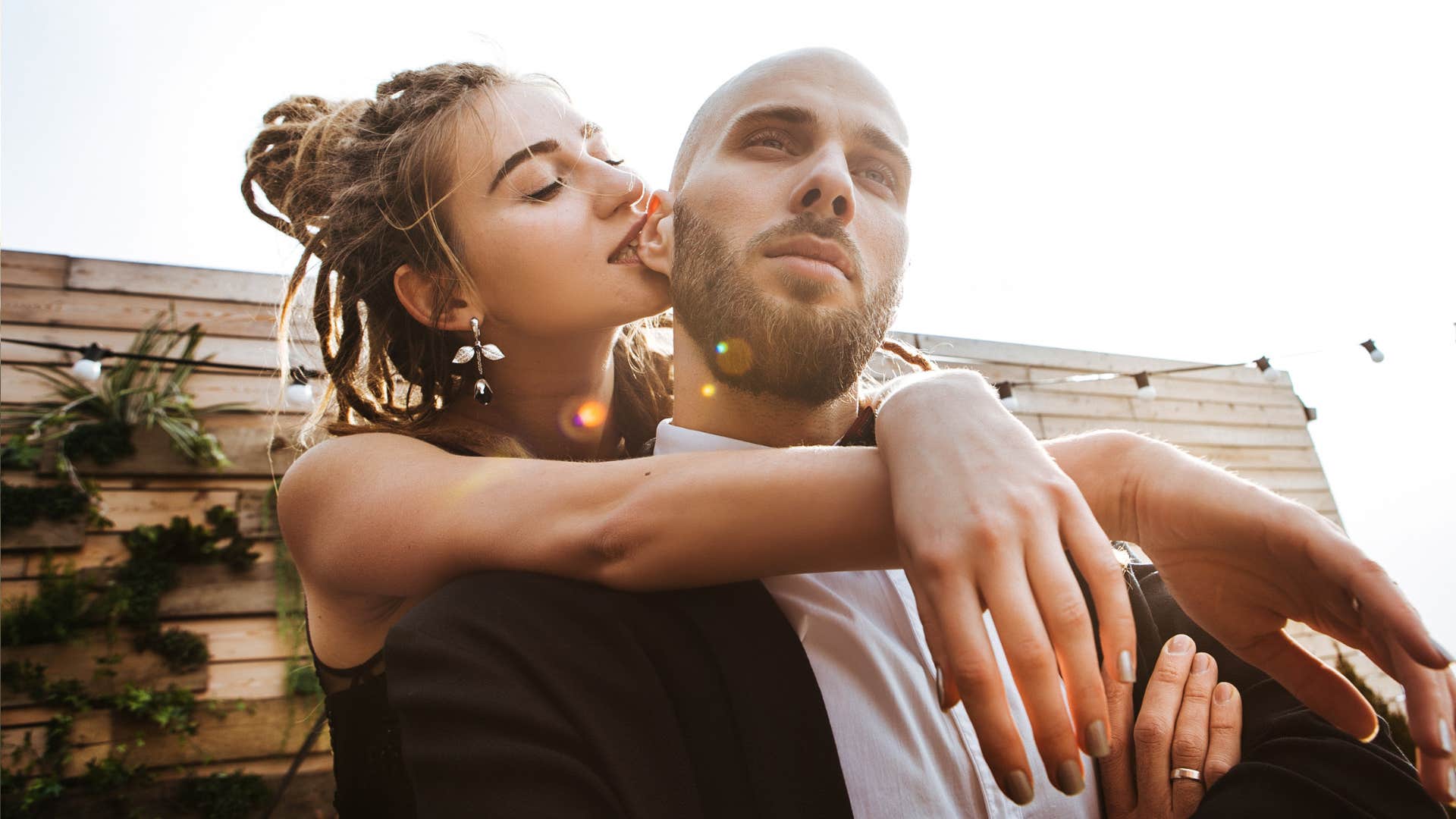 woman with dreadlocks in black dress hugs the shoulders of the man stylish suit