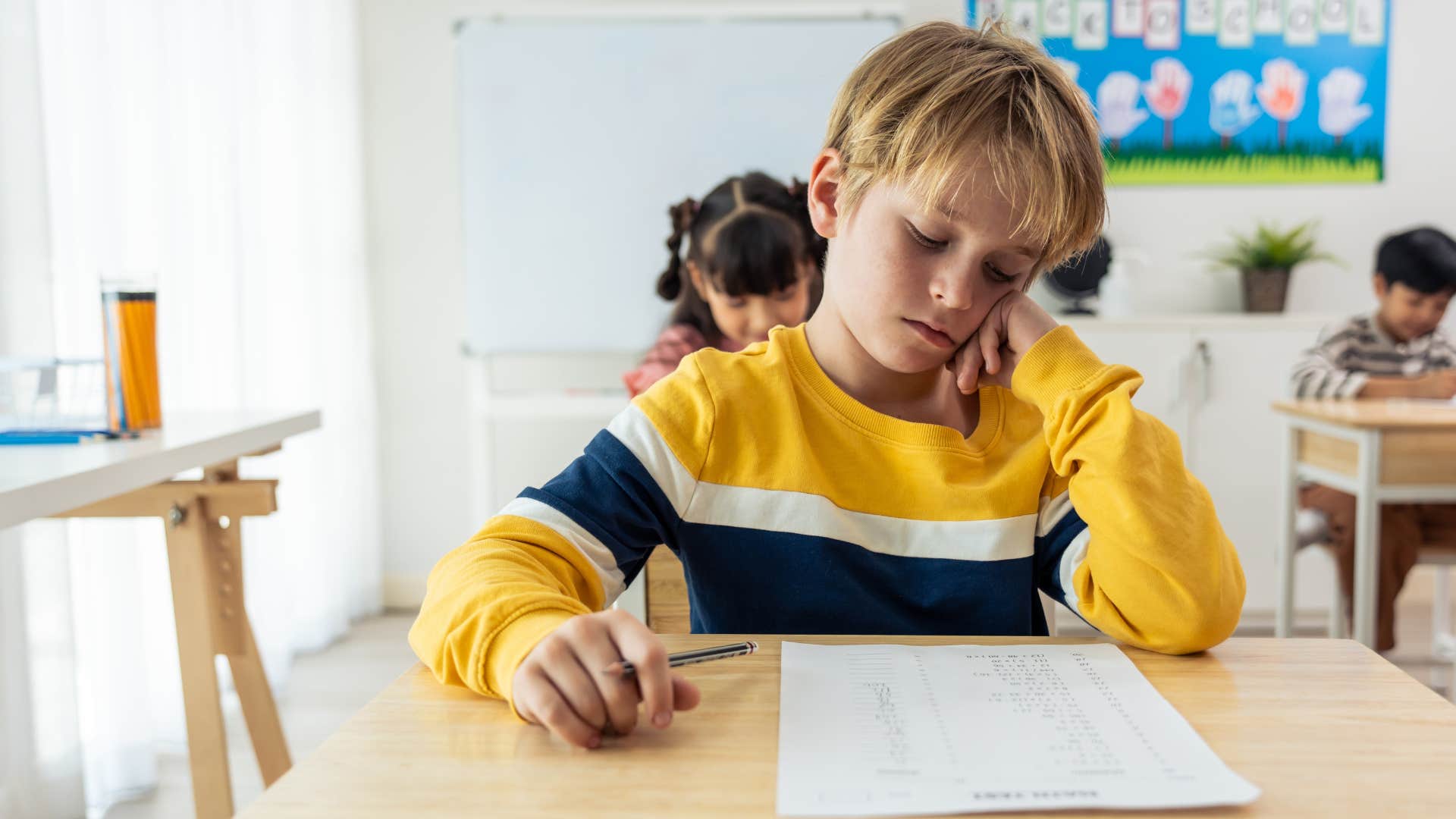 Young student looking sad at his desk.