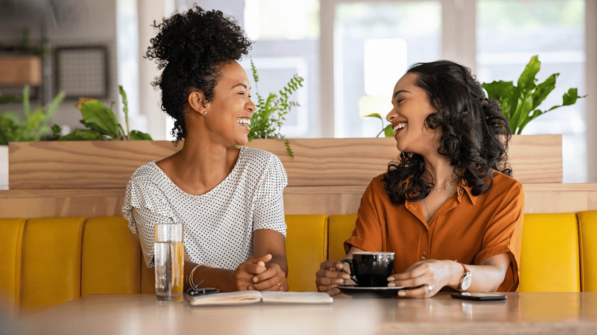 two women talking while drinking beverages