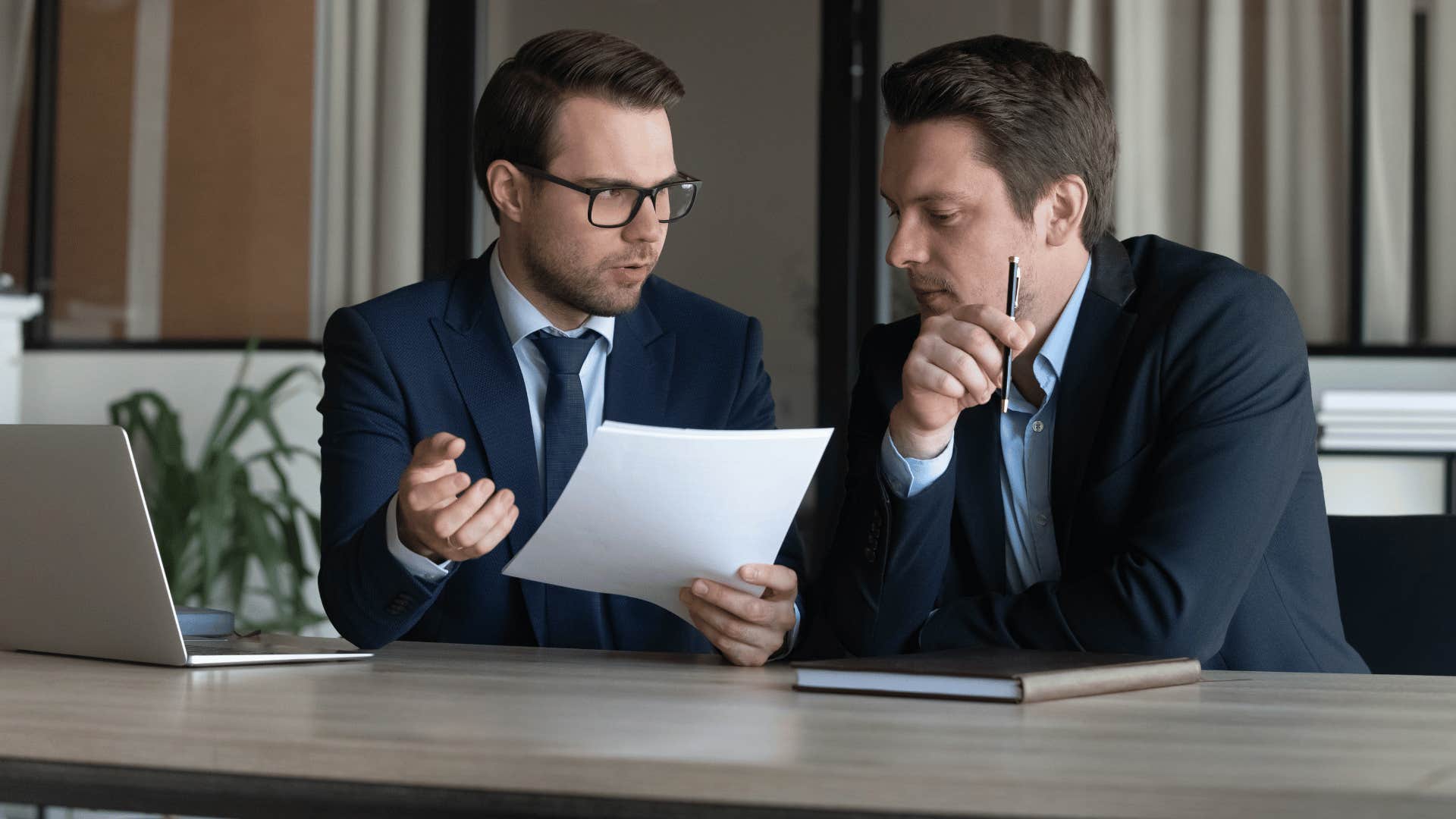 two men discussing paper