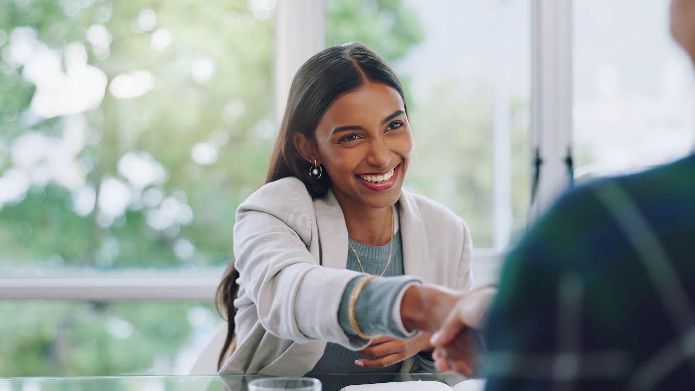 smiling business woman reaching out for a handshake in an interview