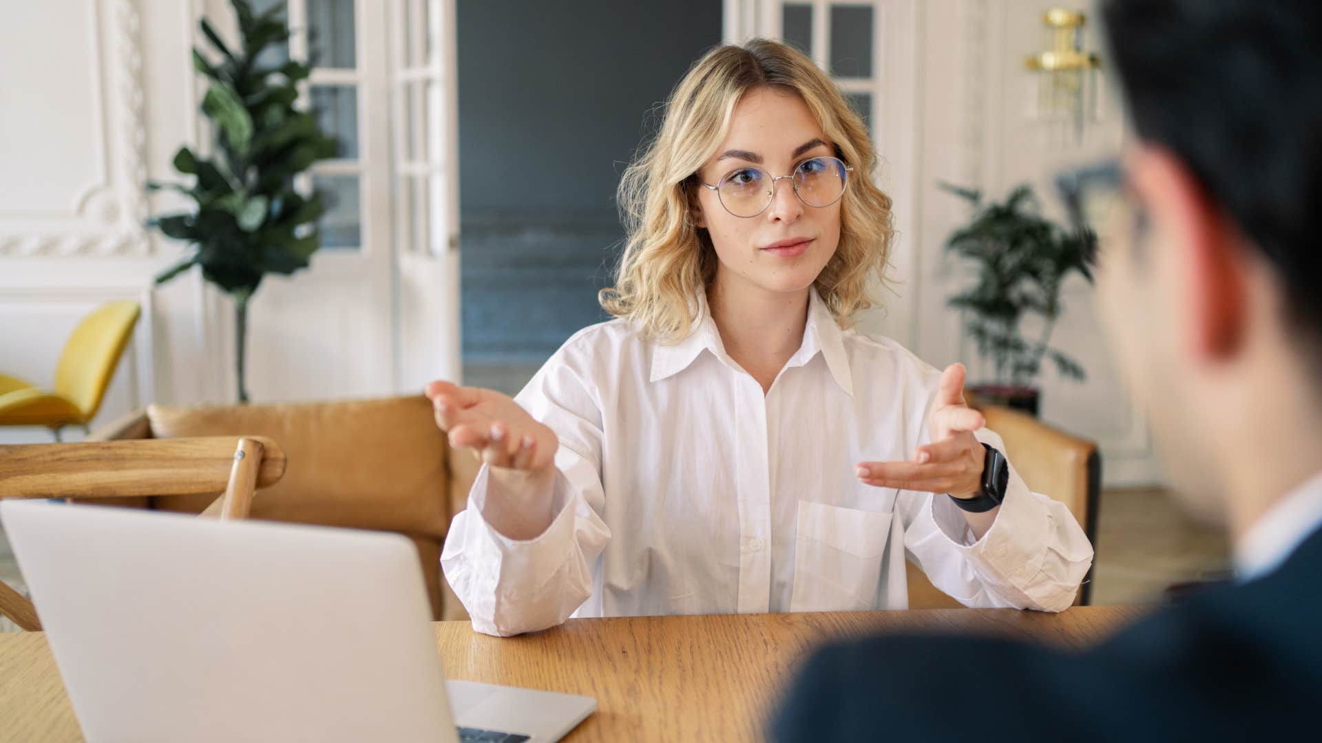 Professional woman talking to a man at her desk.