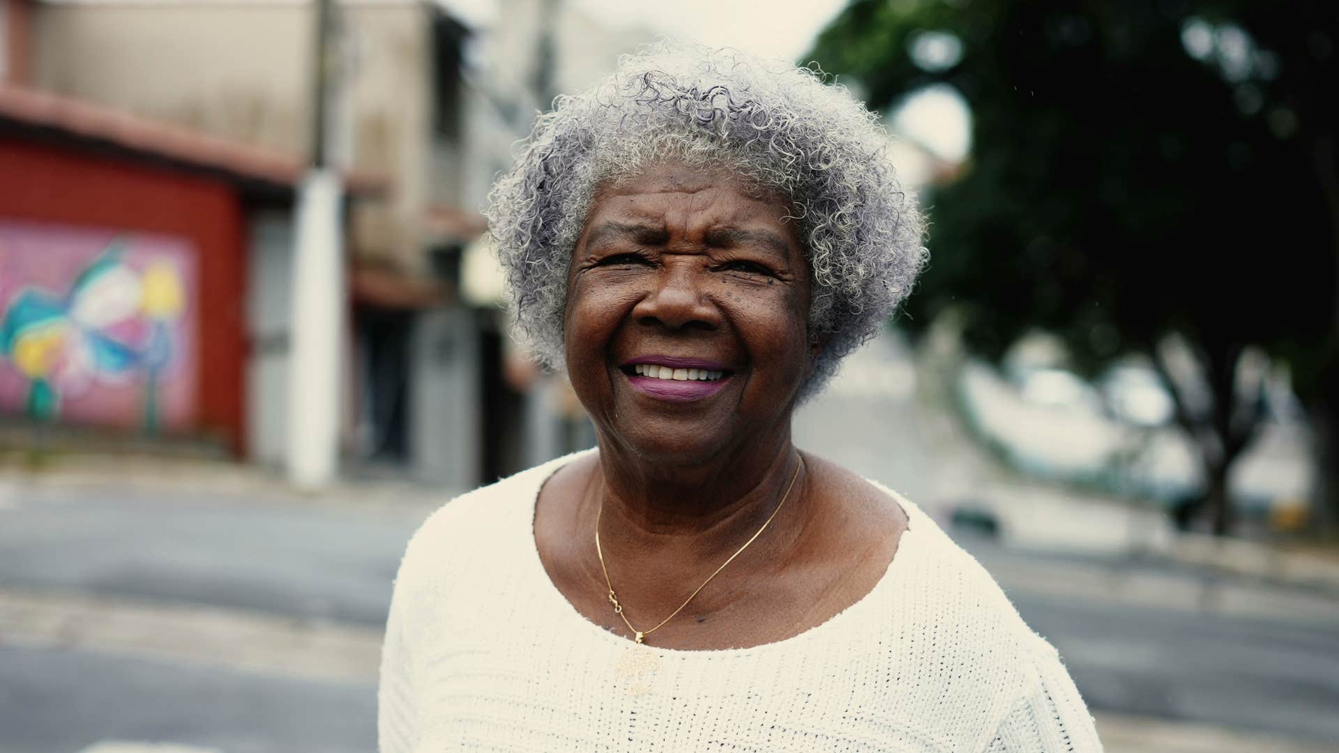 Older classy woman smiling on the street outside.