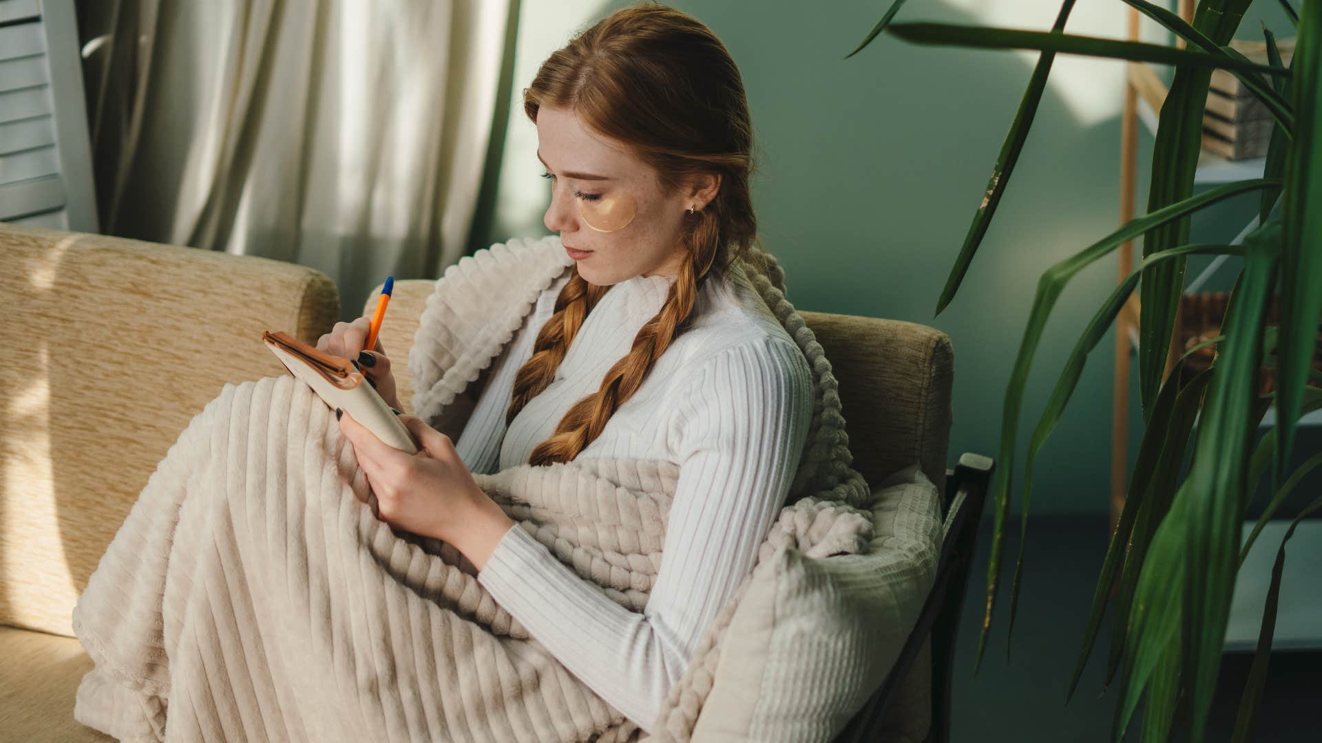 Woman writing in her journal on the couch. 