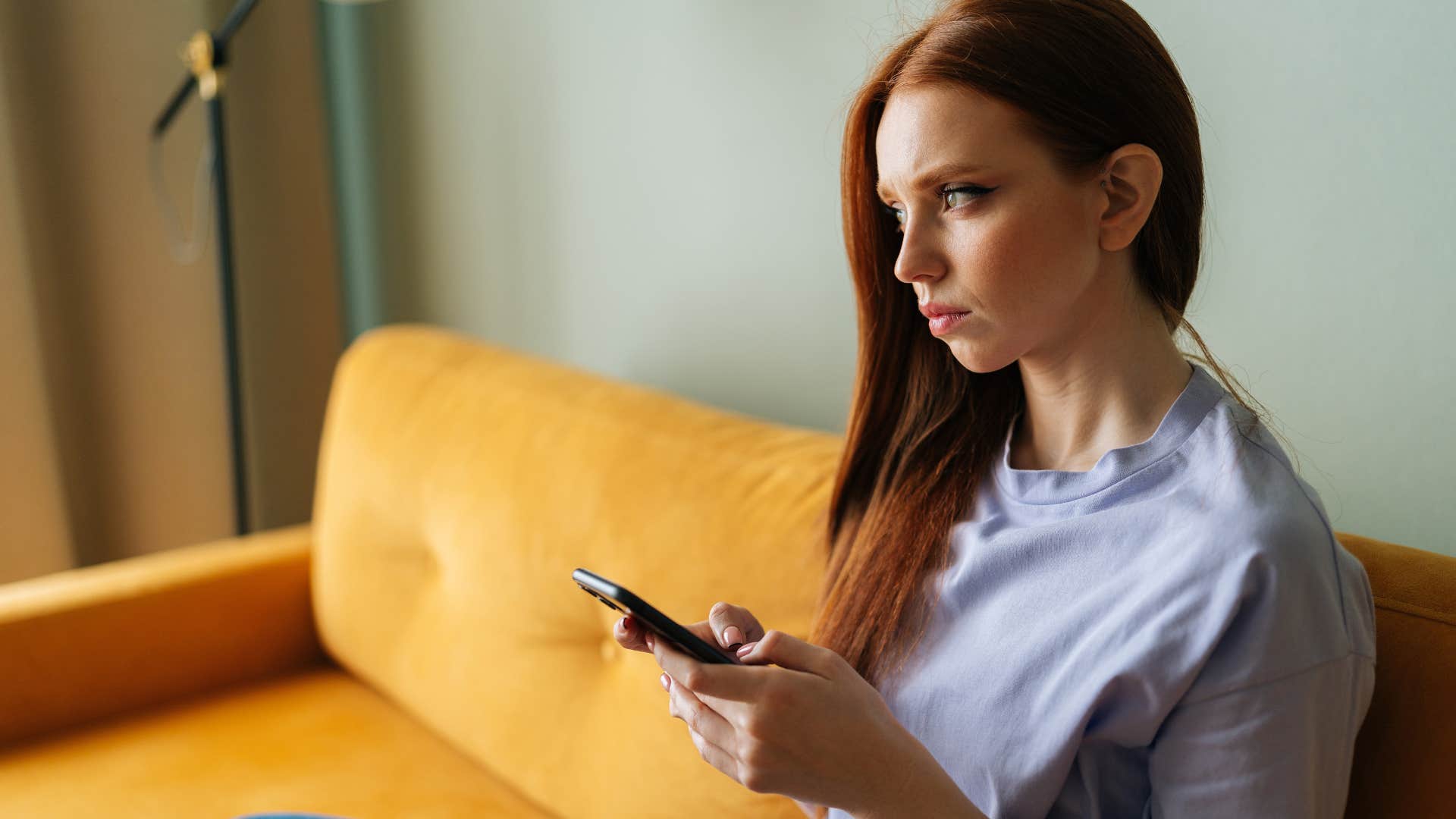 Woman looking upset staring at her phone.