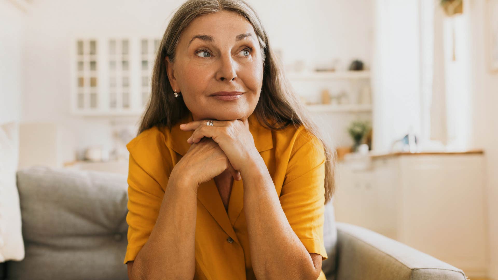 Older classy woman smiling on her couch.