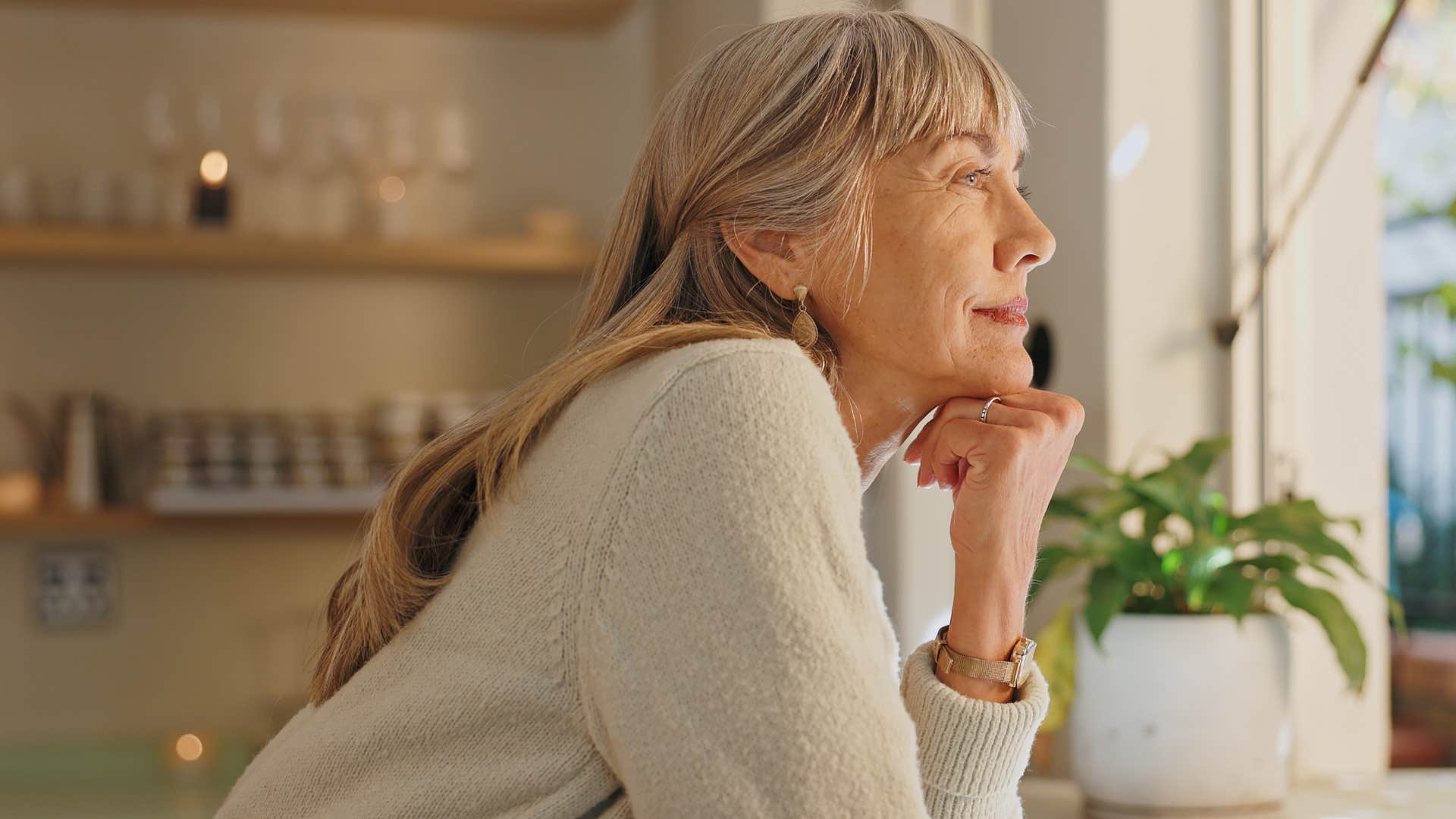 Older woman looking out a window.