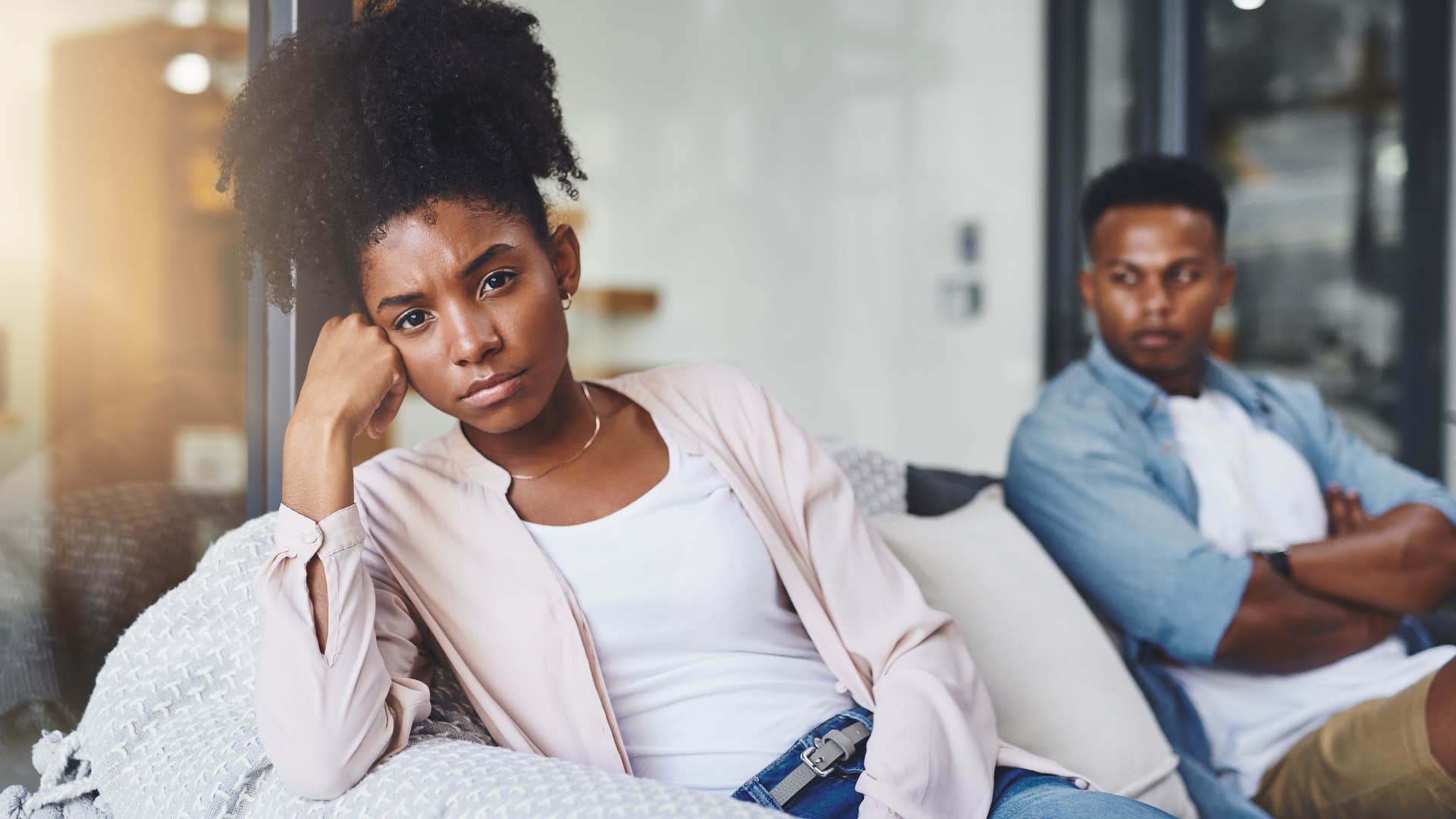 Classy woman looking away from her partner on the couch.