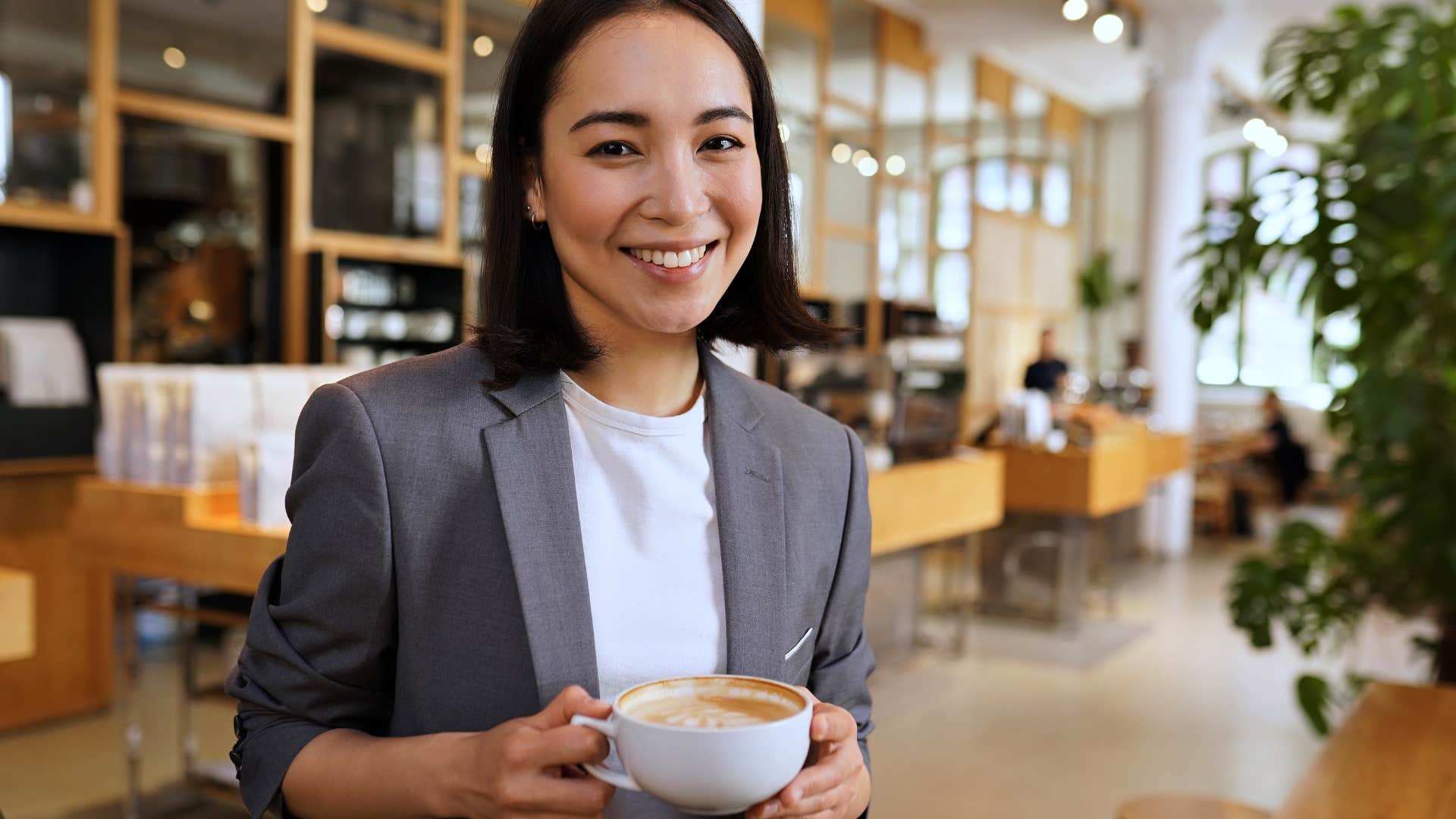 Gen Z woman smiling and holding a cup of coffee