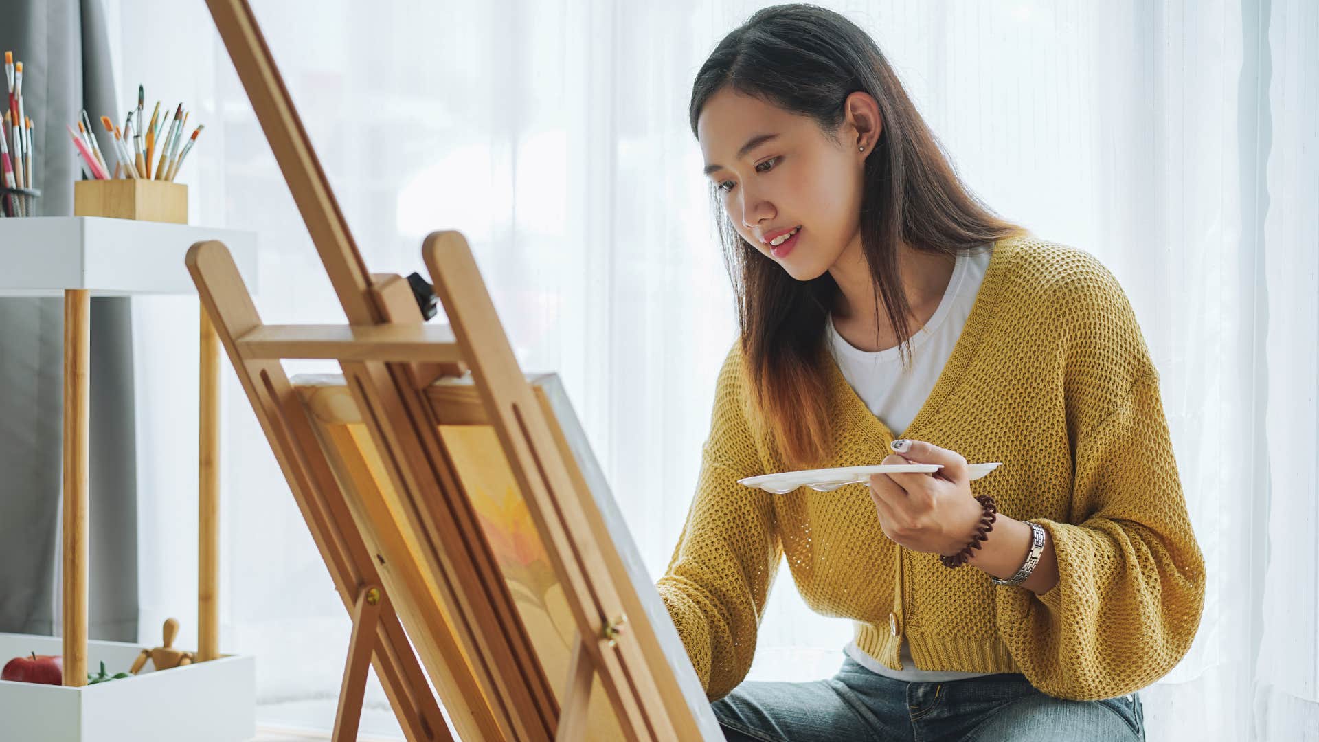 Woman smiling while painting on a canvas