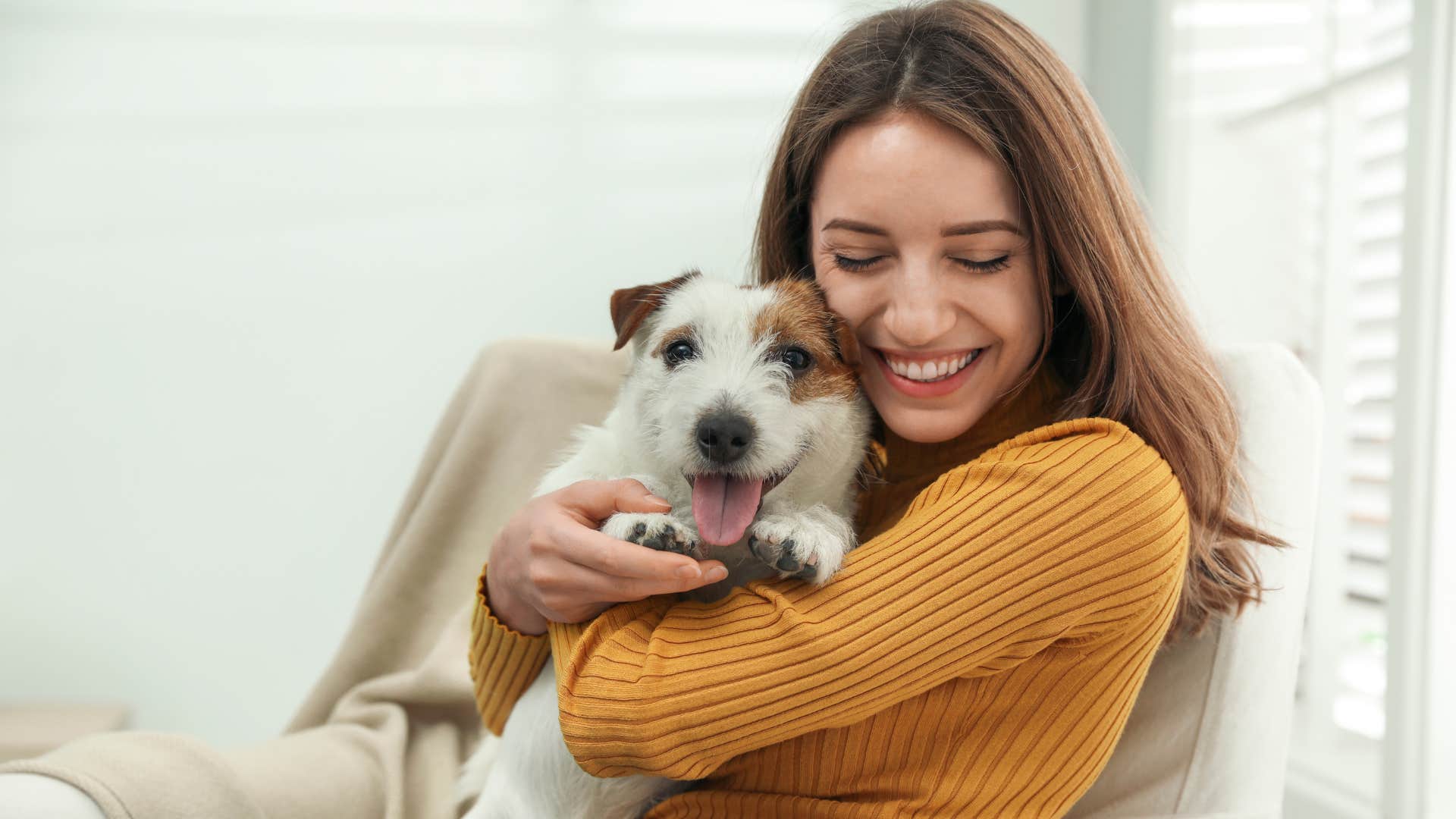 Woman smiling and holding her dog in her arms