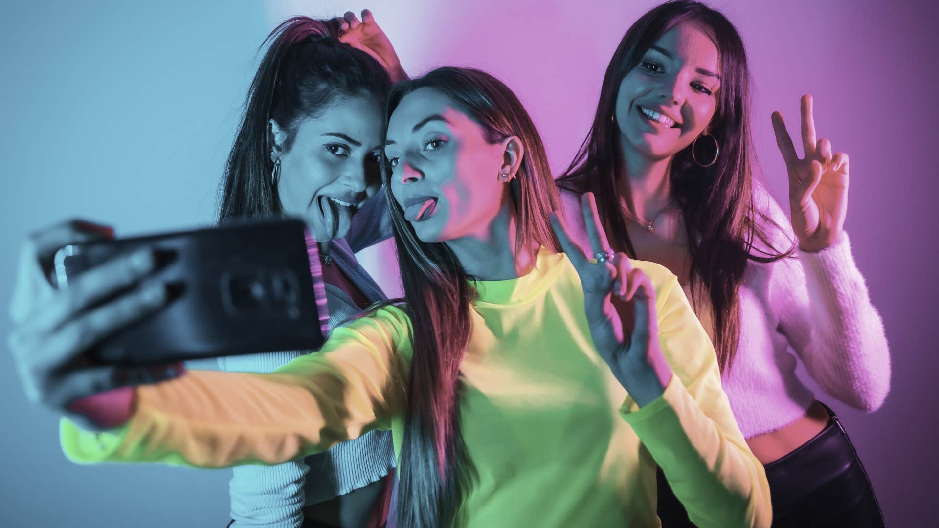 Gen Z women smiling for a photo in neon lighting