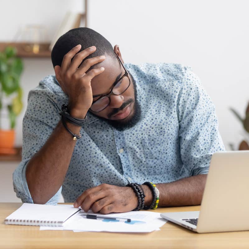 tired businessman sitting at desk in front of laptop