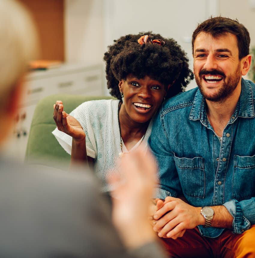 Happy couple smile while talking to therapist