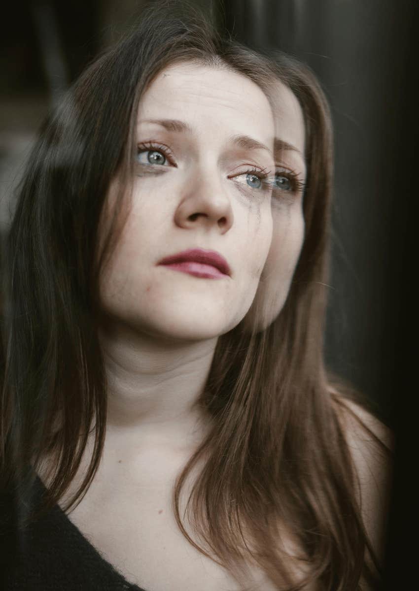 crying young woman looking out of window