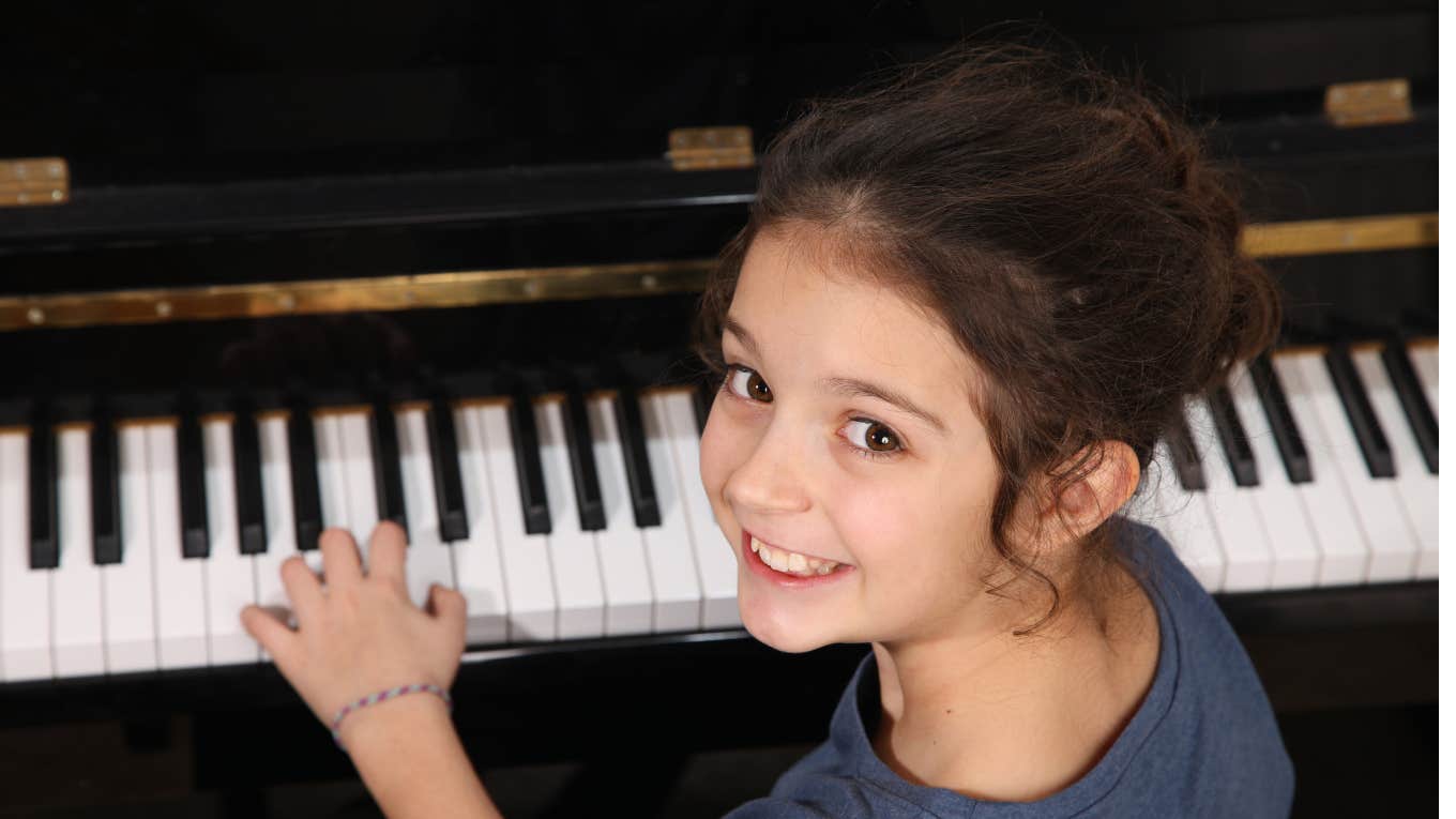 Little girl smiling while playing piano