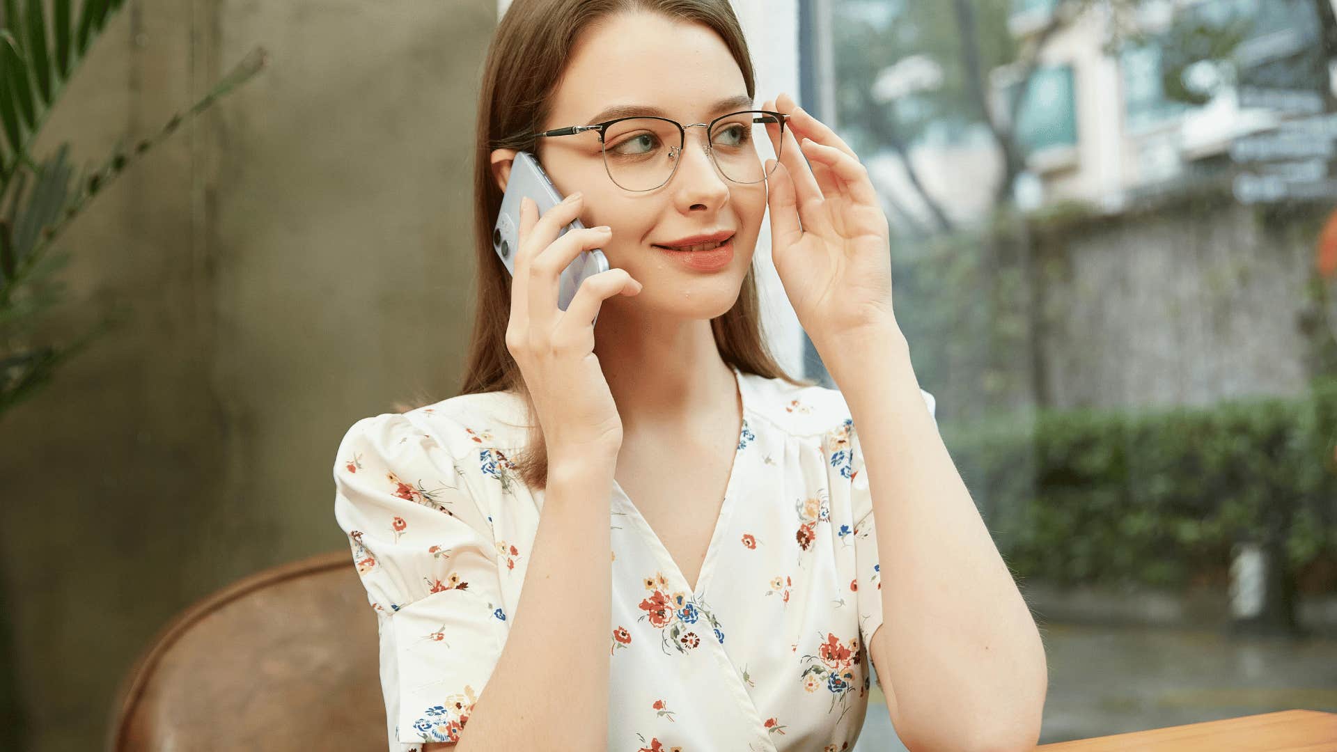 woman on phone fixing glasses