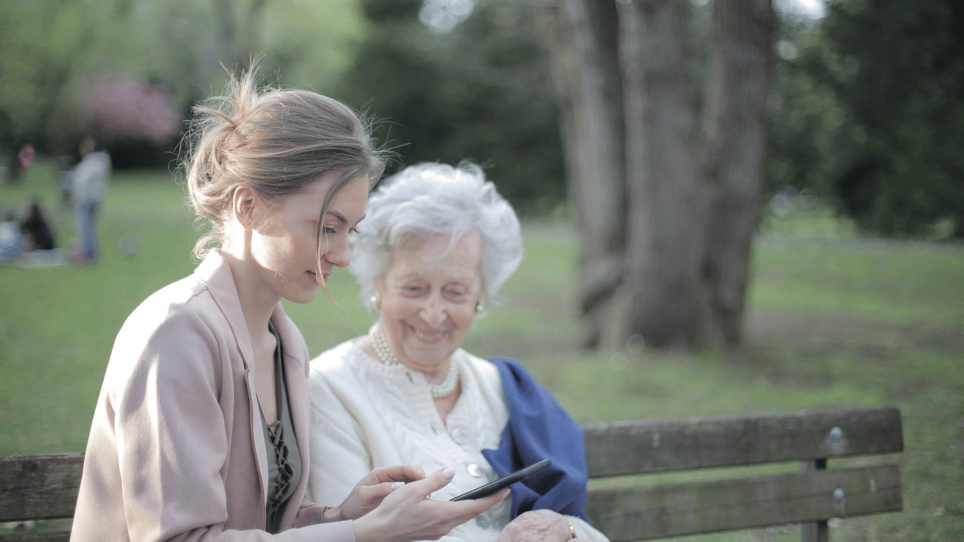 younger woman with older woman sitting on park bench