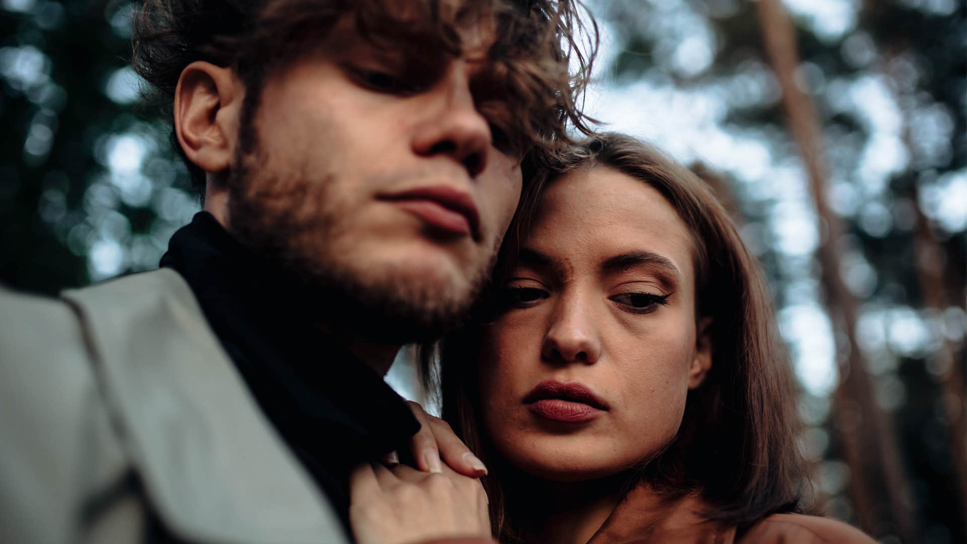 couple in love in the forest at sunset on a date hugging in a coat in the summer